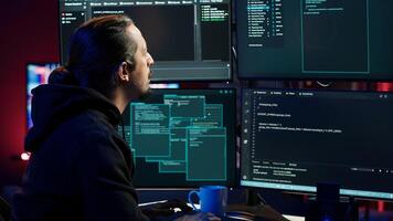 Hacker typing fast on keyboards, rushing to finish developing spyware software, using it to gather data from users computers without their knowledge. Scammer writing malicious code, camera A photo