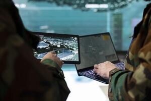 Troopers comparing gathered radar information on laptop and tablet, communicating with allied forces and transmitting real time data from surveillance satellite footage. Joint operations. photo