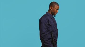 Bored security guard preventing criminal activity, patrolling around premises to deter criminals. Portrait of weary bodyguard walking around, lacking activity, studio background, camera B photo