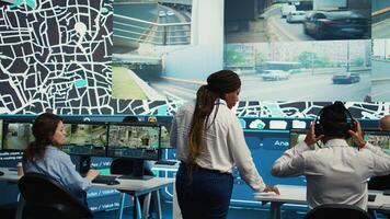 Team leader gives order tracking details to her employees in control center, people working together to guide delivery trucks on less busy routes. Using surveillance footage and gps. Camera B. photo