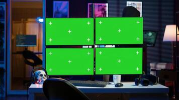 Hacker using isolated screen multi monitor PC setup, doing computer sabotage using ransomware. Cybercriminal walking with laptop, breaching firewalls in apartment with mockup displays, camera A photo