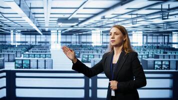 System administrator in high tech data center looking at hologram visualization. Computer scientist working on securing server terminals using AR tech, preventing hacker attacks, camera B photo