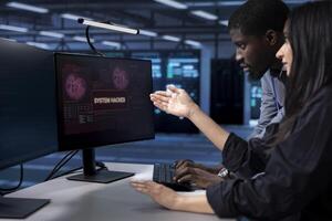 Programmers doing teamwork in server hub trying to protect hardware from hacker stealing information. Colleagues in data center workspace trying to fix security breach alert caused by virus photo