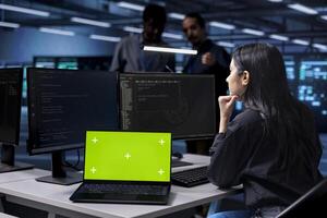 Woman working on laptop with isolated screen monitor in modern data center. IT professional doing IT infrastructure management on server racks in high tech environment using mockup notebook photo