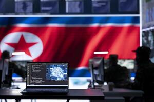 Military personnel working in a command post with a North Korea flag on big screen, monitoring activity via gps and world map. Soldiers developing warfare tactics for scams. photo