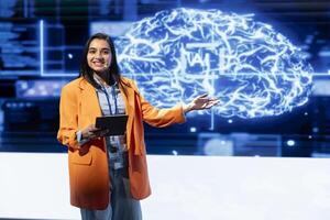 Happy presenter talking at AI summit using mic and tablet, sharing industry expertise to audience. Cheerful technician holding device, exploring latest AI products and services at tech event photo