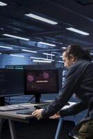 System administrator in server room frightened by sensitive data threatened by hacking attack on computers. Afraid man jumping out of desk chair, rushing to save data center from unauthorized access photo
