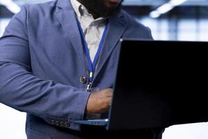 Admin in data center implementing backup solutions to protect against data loss using laptop, ensuring efficient recovery processes. Close up of worker identifying and resolving technical issues photo
