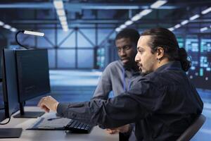 Engineers doing maintenance in server hub to extend equipment life span and avoid downtime. Coworkers monitoring mainframes for overheating problems and power fluctuations photo