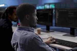 Computer scientists checking for signs of imminent failure in data center equipment. Employees working at PC desks to preventing server clusters damages, monitoring critical systems photo