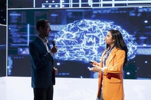 Jolly presenter inviting engineer on stage during global IT conference to talk about subjects such as enterprise AI, deep learning, big data, neural networks and cognitive computing photo