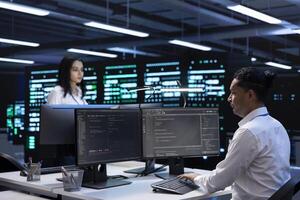 Coworkers in data center using computers to find firewall misconfigurations affecting servers. Colleagues in server room checking systems bottlenecks on PC leading to sluggish data transfer rates photo