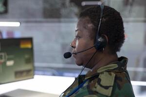 Female IT operator examining real time battlefield data on big screen, collecting intelligence for a reconnaissance defense operation. Military staff provides support for an infantry unit. Close up. photo
