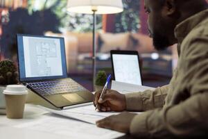 Corporate owner planning an office interior design renovation, reviewing blueprints and collaborating with contractors to create a modern workspace. Evaluating property sketches at home. photo