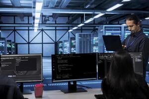 Admin doing yearly checkup to prolong data center electronics life span and avoid downtime. Employee in server room monitoring server infrastructure components using laptop photo