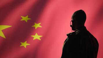 Military dispatcher working for Chinese army relaying info for troops using headset. Radio communications operator isolated over China flag background coordinating soldiers through headphones photo