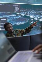 Army specialists use advanced computer systems and big screen to gather intelligence, studying radar satellite data to enhance national security. High tech military control room base of operations. photo