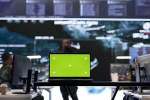 Laptop with green screen display running in military base of operations control tower, space used for gathering intelligence and support secret national defense missions. Command post. photo