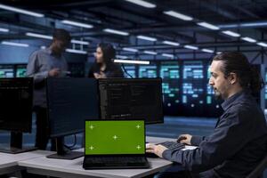 Technician in server hub using green screen tablet to repair equipment storing datasets. IT specialist using mockup device to do debugging on rigs doing computational operations photo