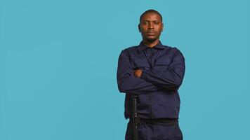 Security guard does surveillance for various organizations and venues, ensuring protection of property and personnel, studio background. Portrait of intimidating man in uniform crossing arms, camera B photo