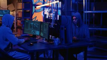 Hackers in dark neon lit underground HQ coding malware designed to exploit network backdoors, using high tech tools to bypass security measures such as logins and password protections photo
