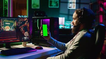 Man watching favorite content creator on isolated screen cellphone showing tips for game he is currently playing. Player stuck on difficult mission, looking online for inspiration on mockup phone photo