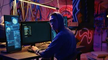 Asian hacker hiding in underground bunker, looking over his shoulder and feeling anxious after stealing data from victims using computer virus, scared about being caught by police photo