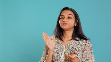 Portrait of envious indian woman mockingly clapping hands, showing frustration, studio backdrop. Resentful sassy person rolling eyes and applauding in jest, feeling irritated, camera B photo