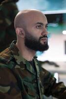 Army captain oversees special operation to gather intelligence, analyzing important data for a national defense mission. Major targeting enemy vessels on radar CCTV system in power base. photo