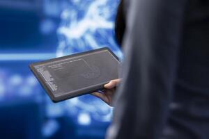Programmer using tablet to maintenance artificial intelligence neural networks. Close up shot of computer scientist using AI system aiding in processing and transmitting information photo