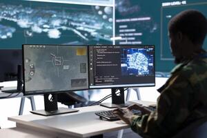 Soldier working with AI intelligence on pc in control room, processing live data on cctv satellite systems. Surveillance efforts to support field missions and defense operations, national security. photo