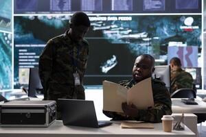 Team of army troops collaborates on intelligence gathering and data processing, helping a national defense mission with crucial real time information. Military drone control personnel in power base. photo