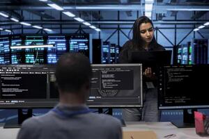 Computer scientists in data center running system diagnostic tests on laptop to fix problems. IT professionals in server room deploying error checking utilities on notebook to fix network issues photo