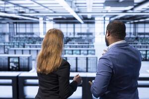 Management team overseeing data center after configuring network infrastructure such as routers, switches and firewalls. Colleagues in server room looking for technical errors photo