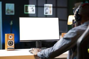 Gamer using headphones to discuss with mates while playing online videogame on isolated screen monitor. Man enjoying coop game with friends on mockup computer display, chatting on internet photo