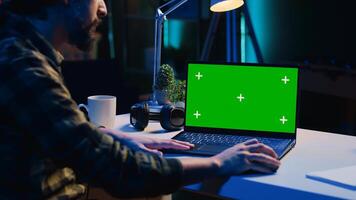 Teleworker in living room office using chroma key laptop to analyze sales report and plan business development. Remote worker doing project research, typing on green screen device keyboard photo