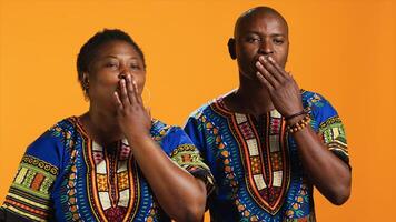 Ethnic couple blowing air kisses in front of camera, doing romantic flirty gesture in studio and sharing love. African american married people sending kiss to someone, affection symbol. photo
