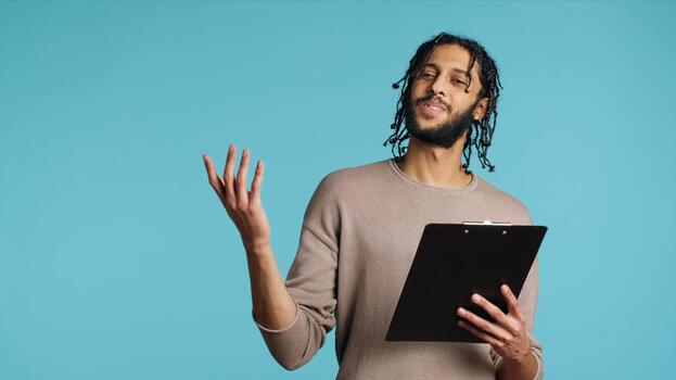 público altavoz leyendo desde portapapeles archivos, preparando discurso, ensayando antes de haciendo discurso. medio oriental orador narración monólogo, aislado terminado estudio fondo, cámara un foto