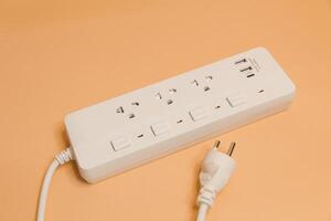 Electrical plug in outlet socket at home, Electrical plug in outlet socket at home, Energy efficiency concept, Power strip with extension cord on beige background, top view. photo