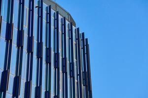 Close-up of modern glass building facade with geometric patterns reflecting sky. Contemporary architectural design. photo