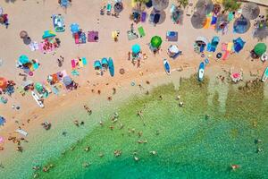 Sea beach with colorful umbrellas and relaxing people, aerial top view. Crowded sandy beach at high season. Tourists at summer holidays in Croatia photo