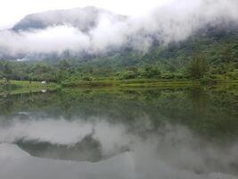 View of lake and and mountain with fog in it photo
