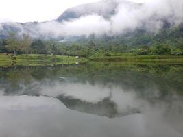 View of lake and and mountain with fog in it photo