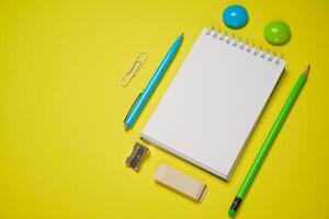 Notebook and pen on a yellow background. Top view with copy space. Stationery photo