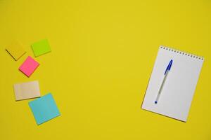 Notebook and pen on a yellow background. Top view with copy space. Stationery photo