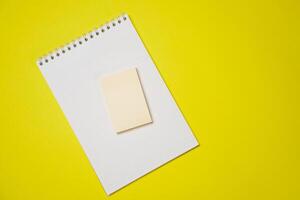Open blank white notepad on a spiral and stickers on a yellow background. photo