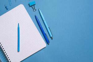 Notebook and pen on a blue background. Top view with copy space. Stationery photo