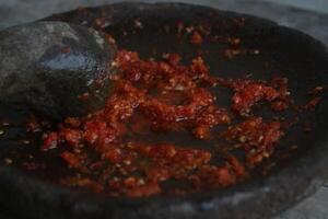 Sambal cobek or traditional Indonesian chili sauce, made from chilies, spices and other kitchen spices. made using a stone mortar and pestle. suitable for menu books. photo