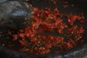 Sambal cobek or traditional Indonesian chili sauce, made from chilies, spices and other kitchen spices. made using a stone mortar and pestle. suitable for menu books. photo