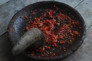 Sambal cobek or traditional Indonesian chili sauce, made from chilies, spices and other kitchen spices. made using a stone mortar and pestle. suitable for menu books. photo